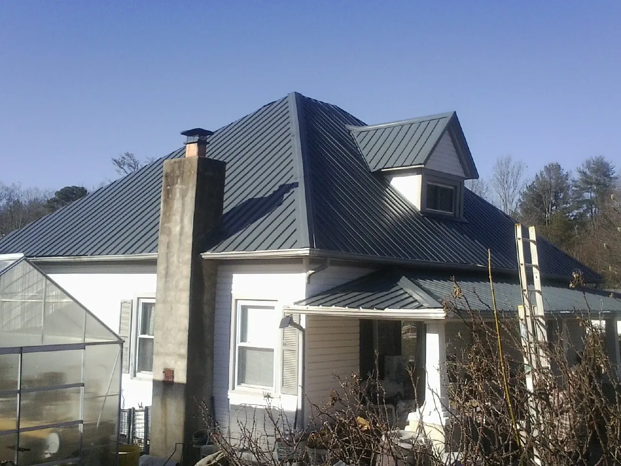 Dark blue standing seam metal roof on a white farmhouse with dormer — Slate & Tile Roof Repair by Roofing Brothers in York Harbor
