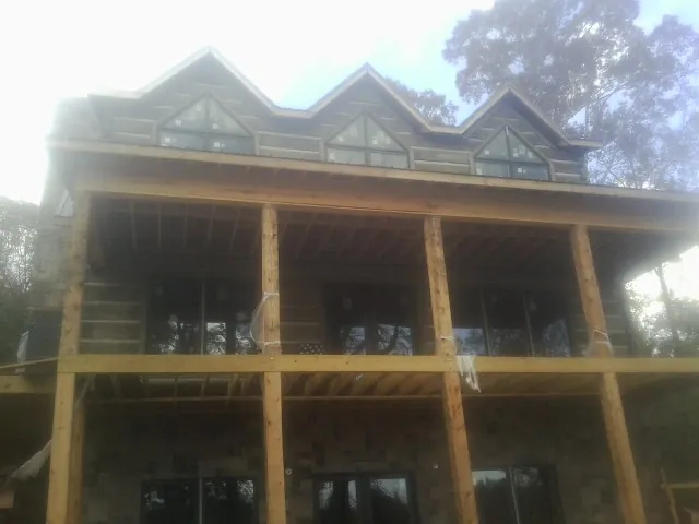 Dormers and porch framing on a large log home under construction — Roof Coating work by our crew in York Harbor