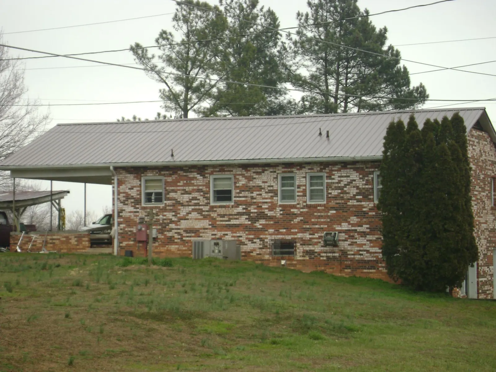 Gray metal roof on a brick split level home with a carport in York Harbor