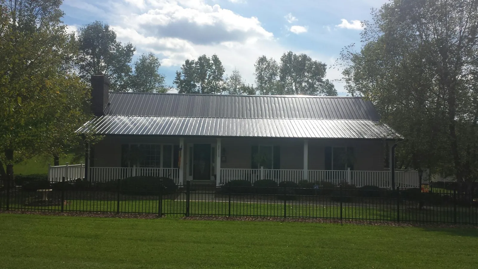Gray metal roof on a brick ranch with a full width front porch — Gutter Guard Installation work by our crew in York Harbor