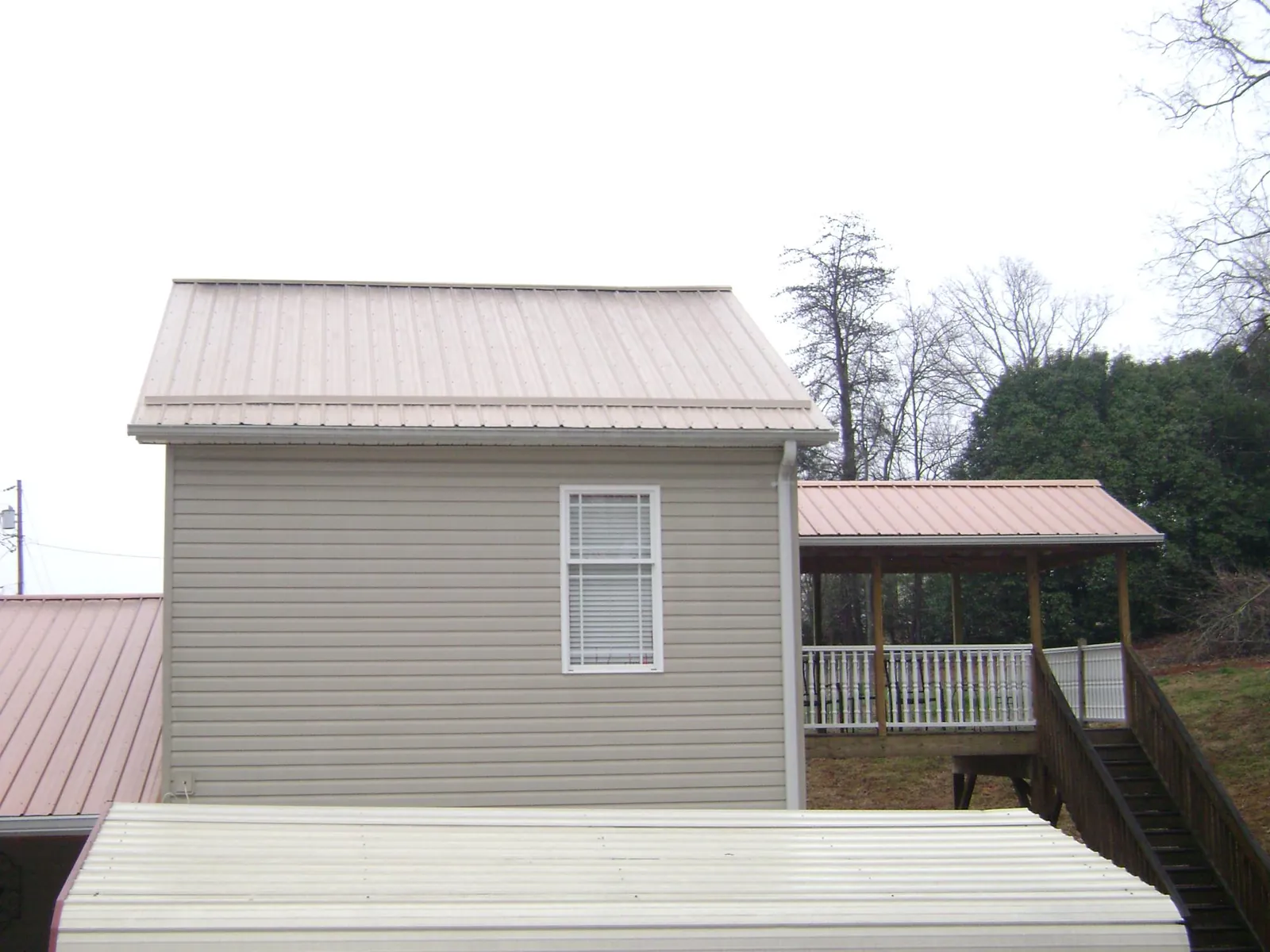 Tan metal roofs on a two story addition and attached porch, from a Roof Replacement job in York Harbor