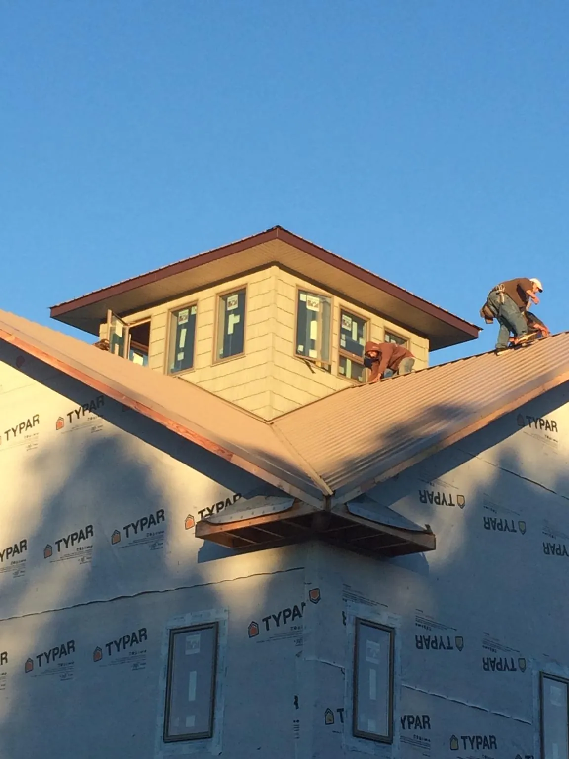 Roofers working around a rooftop cupola on a new metal roof at sunset — Roof Waterproofing in York Harbor by Roofing Brothers